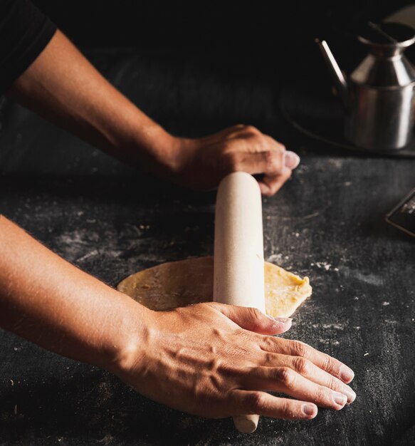 Close-up person spreading dough with rolling pin