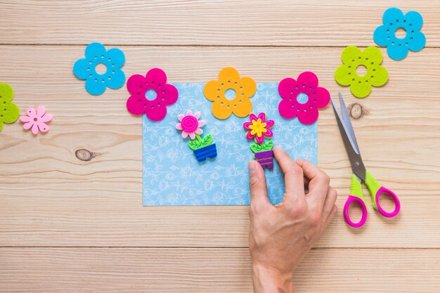 Close-up of a person sticking flower patch on blue card