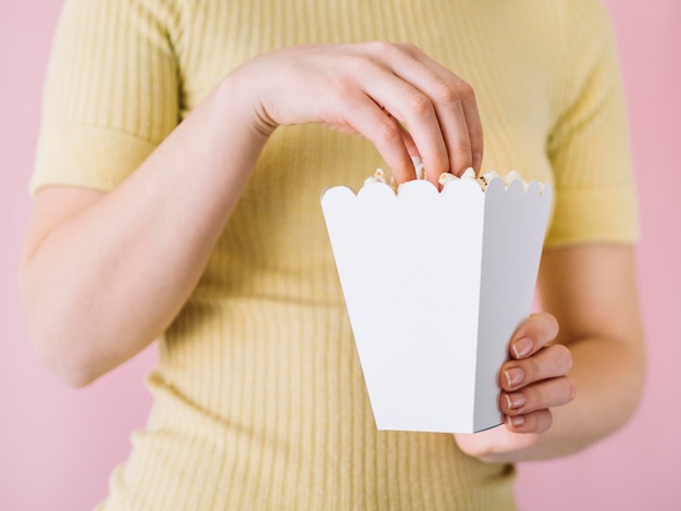 Persona del primo piano che prende popcorn salato