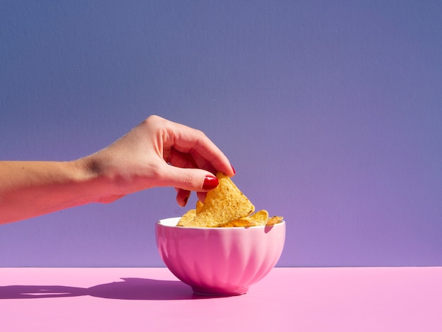 Close-up person taking tortilla from a pink bowl