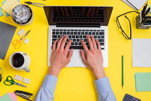 Close-up of a person typing on laptop over the creative minimal office desk