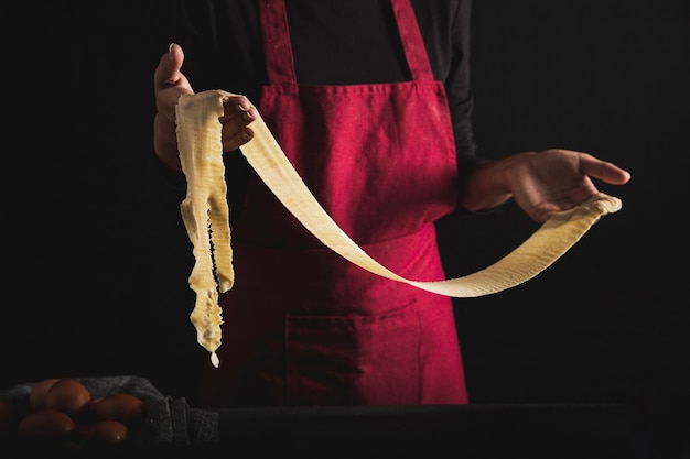 Close-up person with apron holding dough