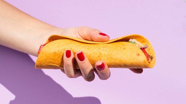 Close-up person with burrito and purple background