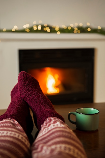 Close-up person with cozy socks near the fireplace