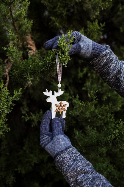 Close-up person with gloves decorating the christmas tree with ornament