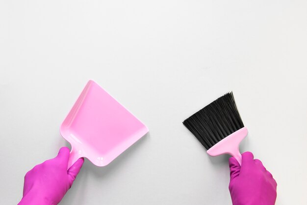 Free photo close-up person with gloves holding small broom