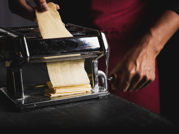 Close-up person with machine and dough 