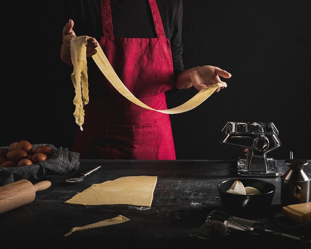 Close-up person with red apron holding dough