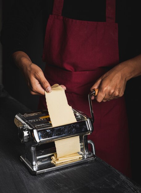 Close-up person with red apron making pasta 