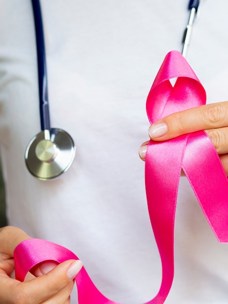 Close-up person with stethoscope and pink ribbon