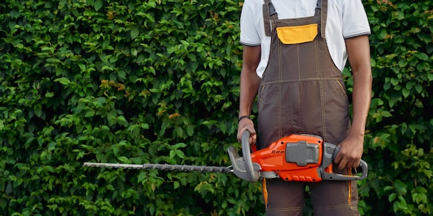 Free photo close up of petrol hedge cutter that holding afro gardener