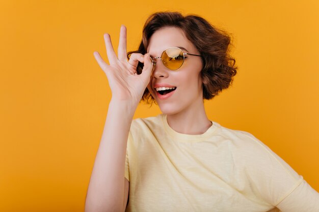 Крупным планом фото очаровательной бледной девушки в желтых солнцезащитных очках