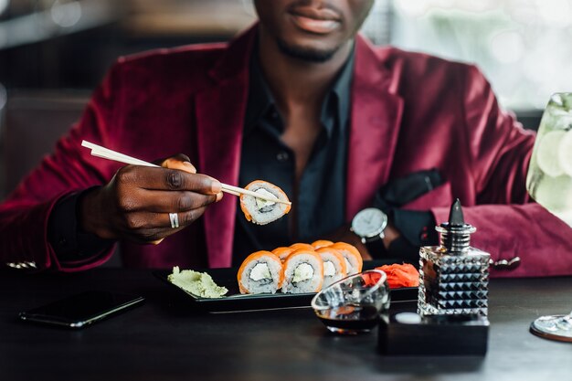 Close up photo. African, american male eating sushi on reataurant.