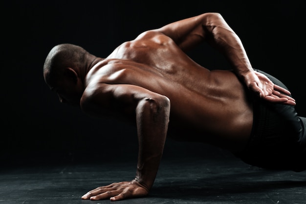 Close-up photo of afro american male athlete doing one-handed push-ups exercise