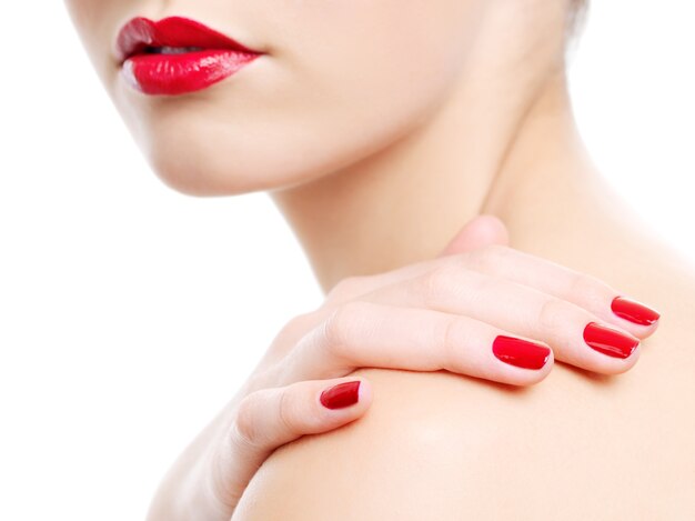 아름 다운 붉은 여성 입술의 클로즈업 사진입니다. 어깨에 미용 매니큐어와 손