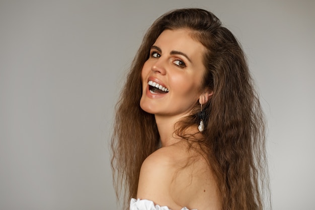 Close-up photo of a cheerful brunette with a jewellery in her ear having a laugh at something funny. Fashion concept
