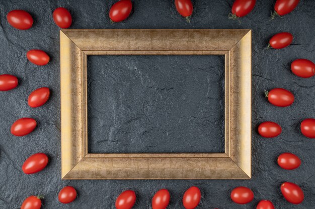 Close up photo of Cherry tomatoes around golden frame on black background. High quality photo