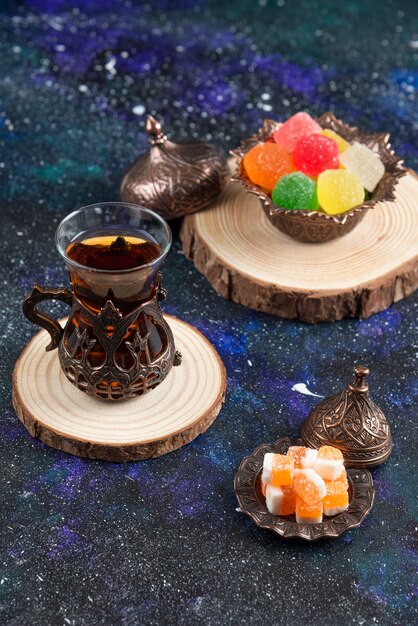 Close up photo of colorful candies and fragrant tea on wooden board