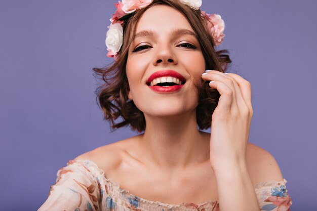 Close-up photo of enthusiastic young woman laughing. good-humoured female model in circlet of flowers.