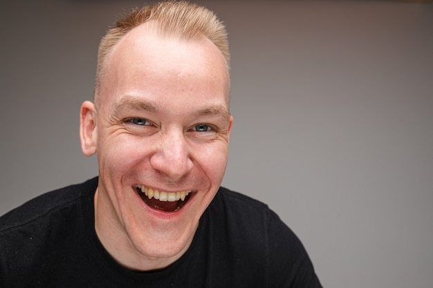 Close-up photo of excited Caucasian man smiling widely and laughing