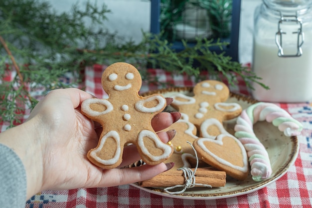 Free photo close up photo of female hand taking cookie from plate.