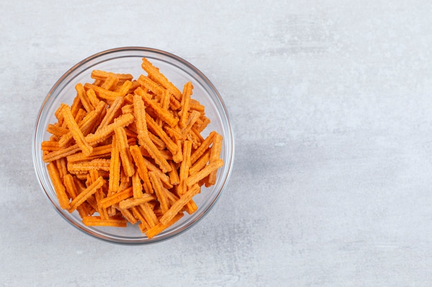 Close up photo of fresh fries in glasses bowl over white.