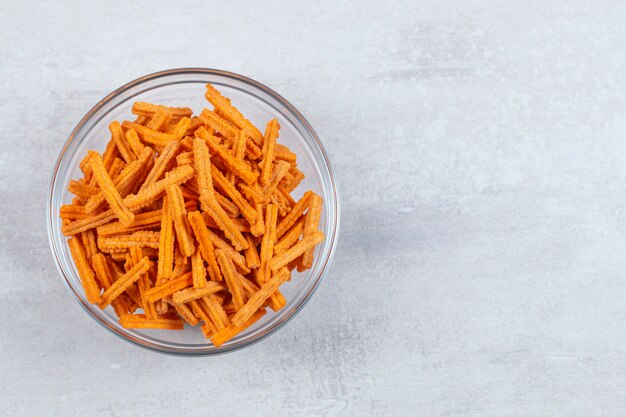 Close up photo of fresh fries in glasses bowl over white.