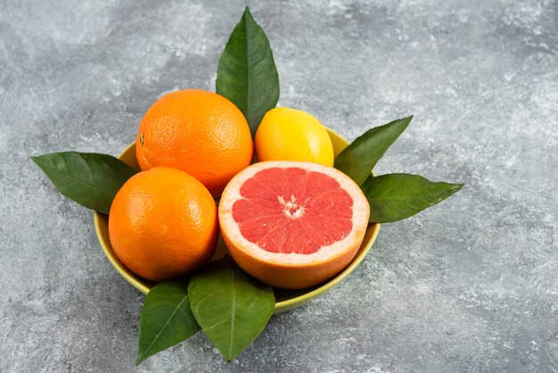 Close up photo of fresh fruits with leaves in ceramic bowl. 