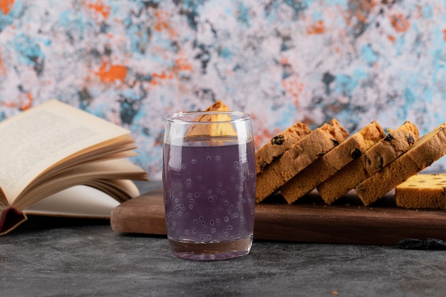 Foto ravvicinata di cocktail di uva fresca con torta a fette e libro.