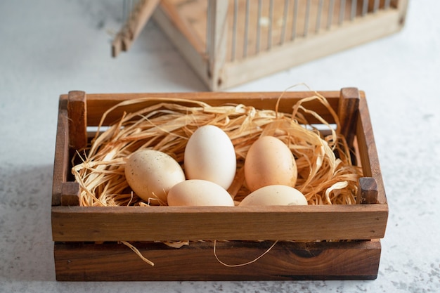 Close up photo of fresh organic chicken eggs on straw in wooden box. 