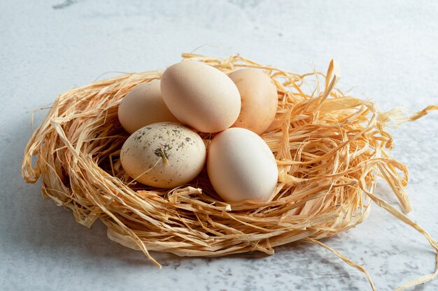 わらの上の新鮮な有機鶏の卵の写真を閉じます。