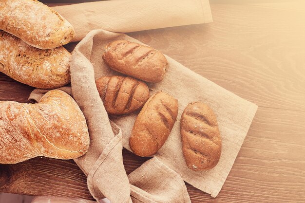 Close-up photo of freshly baked bread products. Delicious freshly bakery products and spikelets of wheat on wooden background.