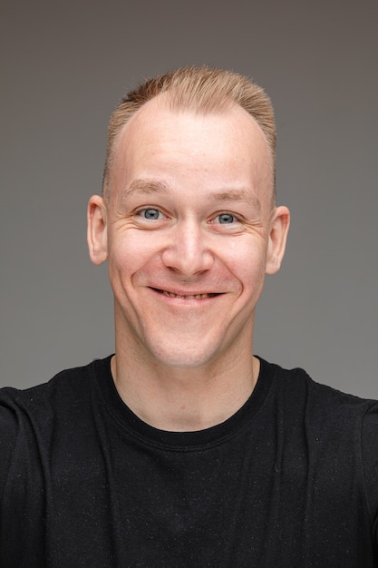 Close-up photo of friendly fair-haired man smiling while posing