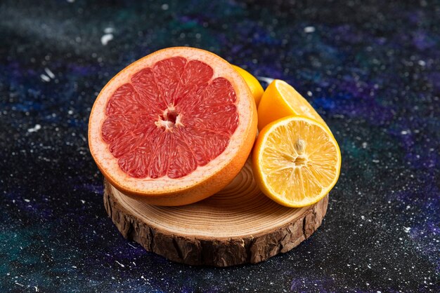 Close up photo half cut grapefruit and lemon on wooden board.