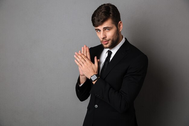 Close-up photo of handsome young man in black suit clap in hands