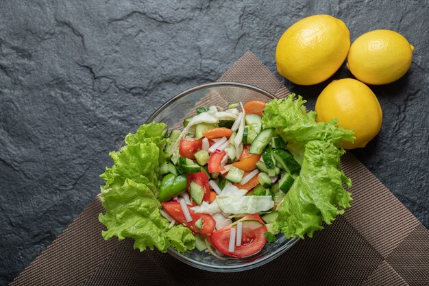 검은 배경에 레몬 건강 야채 샐러드의 사진을 닫습니다. 고품질 사진