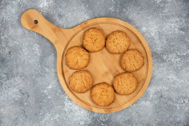 Close up photo of homemade cookies on wooden board over grey table.