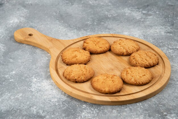 Close up photo of homemade fresh cookies on wooden board over grey surface