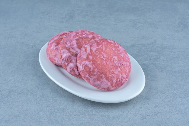 白いプレート上の自家製の新鮮なピンクのクッキーの写真を閉じます。