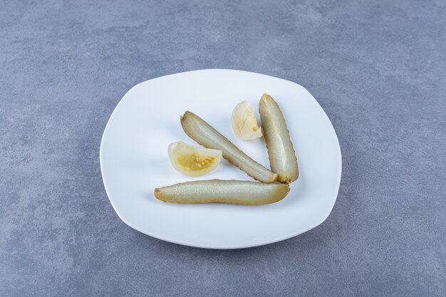 Close up photo of homemade pickle slices on white plate.