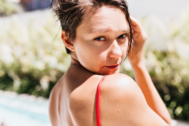 Close-up photo of inspired tanned woman looking over shoulder.