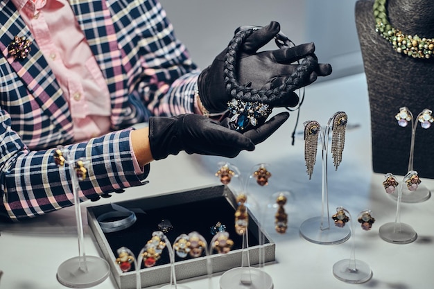 Крупный план работника ювелирных изделий, представляющего дорогое ожерелье с драгоценными камнями в роскошном ювелирном магазине.