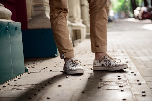Free photo close up photo of man's legs in keds standing at street