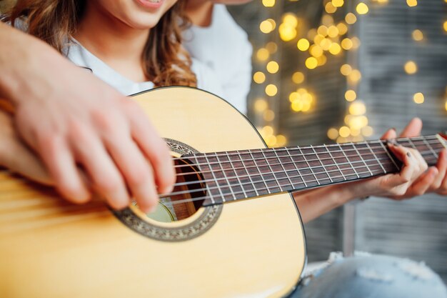 Close up photo. Man teaching girl how  to play acoustic guitar