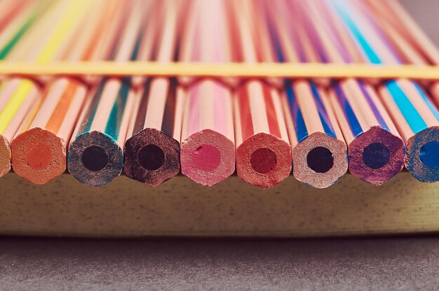 Close-up photo multicolored pencils lying on a yellow notepad.