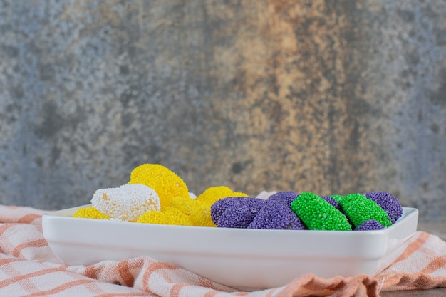 Бесплатное фото Закройте вверх по фото красочного сладкого желе на белой тарелке. пурпурно-зеленый и желтый.