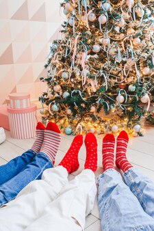 クリスマスツリー​の​そば​の​ウール​の​靴下​で​家族​の​足​の​写真​を​閉じる