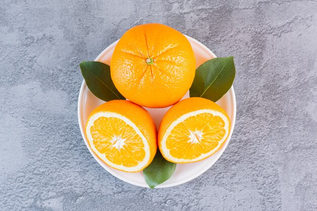 Close up photo of organic lemons on white plate over grey.