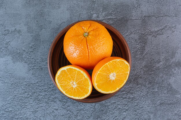 Close up photo of organic oranges in wooden bowl.