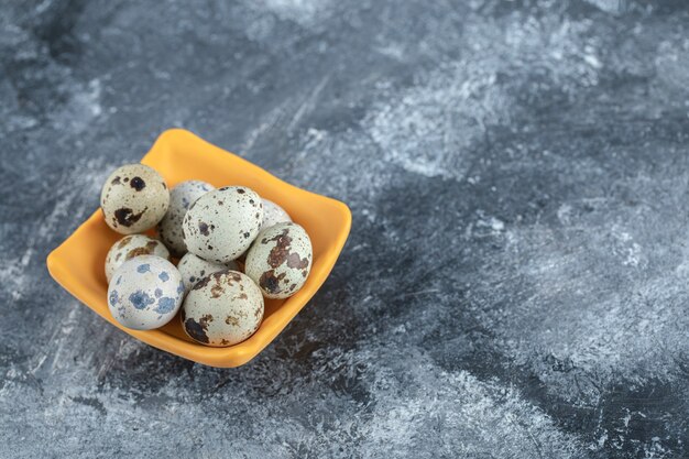 Close up photo of organic quail eggs in yellow bowl.